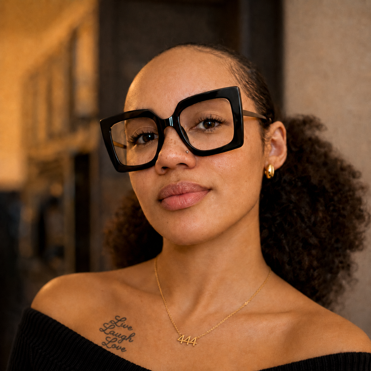 Portia Hunter in a black off-the-shoulder sweater with gold 444 necklace